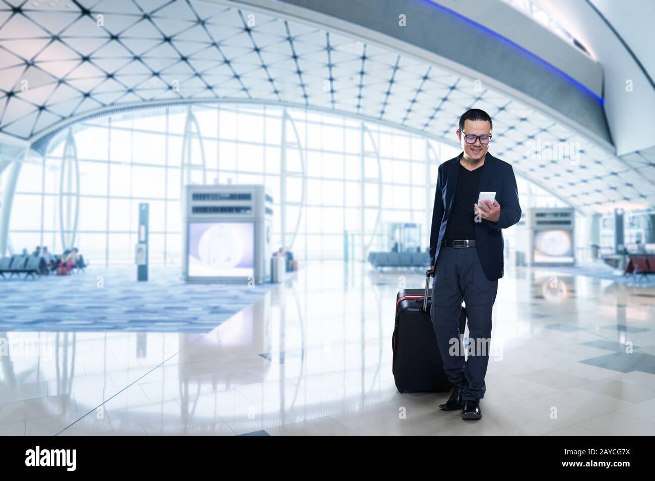 Uomo su smart phone - young business man in aeroporto. Casual urbano imprenditore professionale utilizza lo smartphone sorridendo felice all'interno Foto Stock