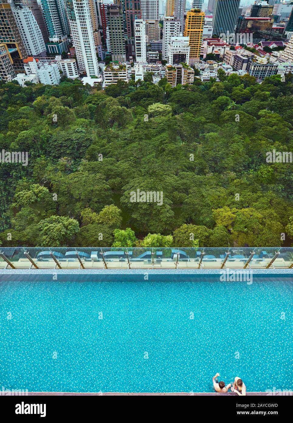 Due persone che si rilassano in piscina con vista città urbana e verde. Vista dall'alto . Foto Stock