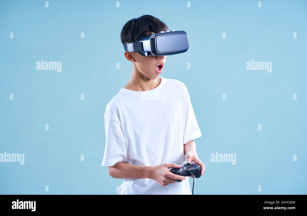 Giovane adolescente che gioca entusiasta con un visore VR per realtà virtuale con controller di gioco . Foto Stock