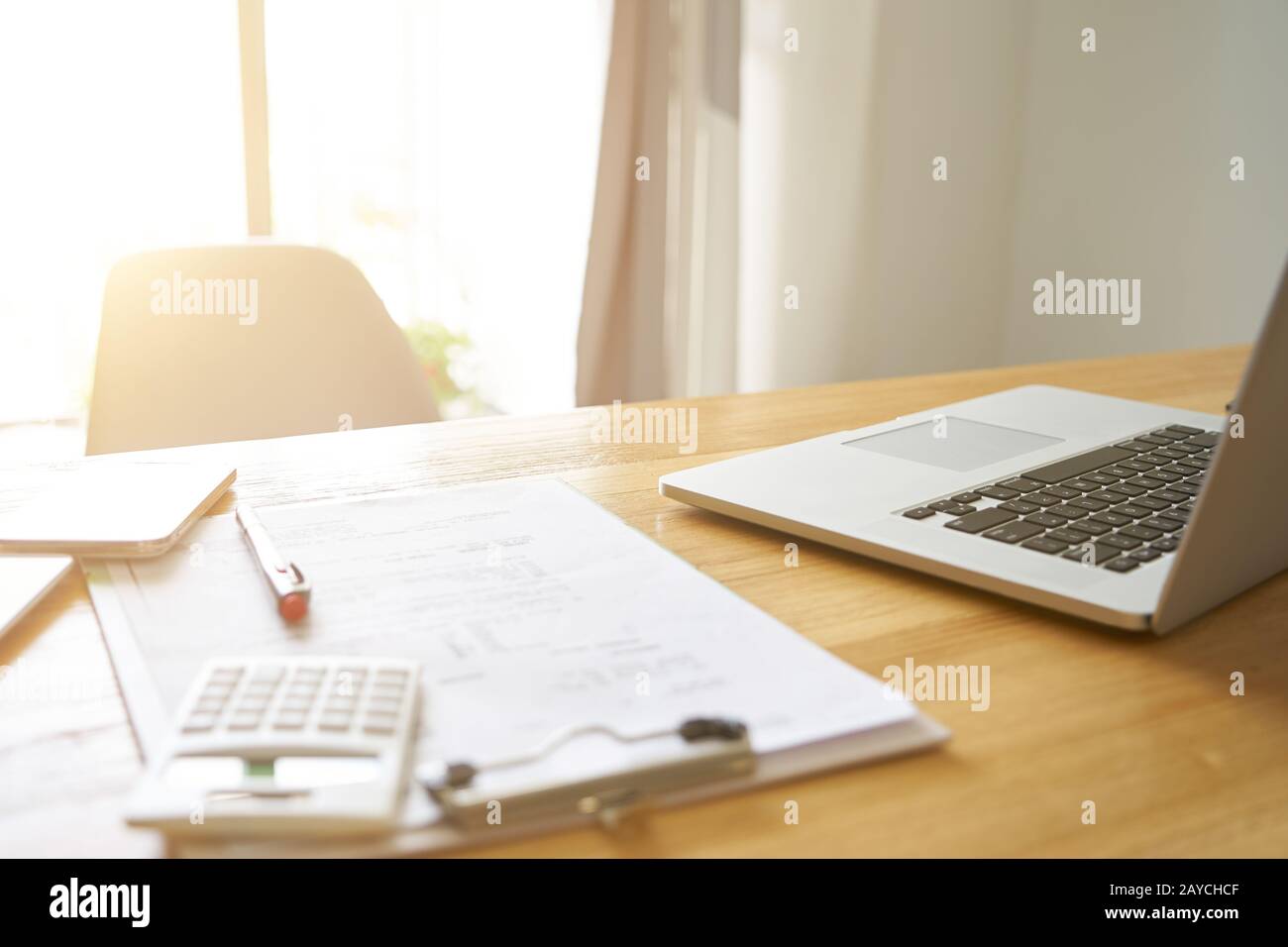 Vista prospettica grandangolare del posto di lavoro dell'ufficio con laptop e smartphone su tavolo di legno con finestra . Foto Stock