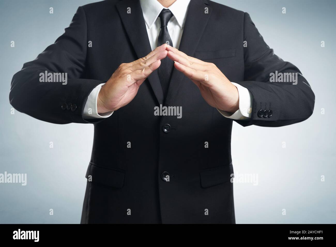 Uomo d'affari in tuta con due mani in posizione per proteggere qualcosa (mettere a fuoco sulla mano Foto Stock