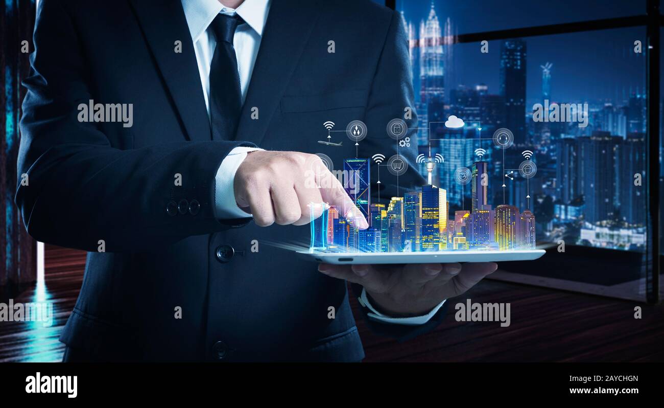 Uomo d'affari che lavora su un tavolo digitale con intelligenza iot e città intelligenti che appaiono sullo schermo virtuale . Foto Stock