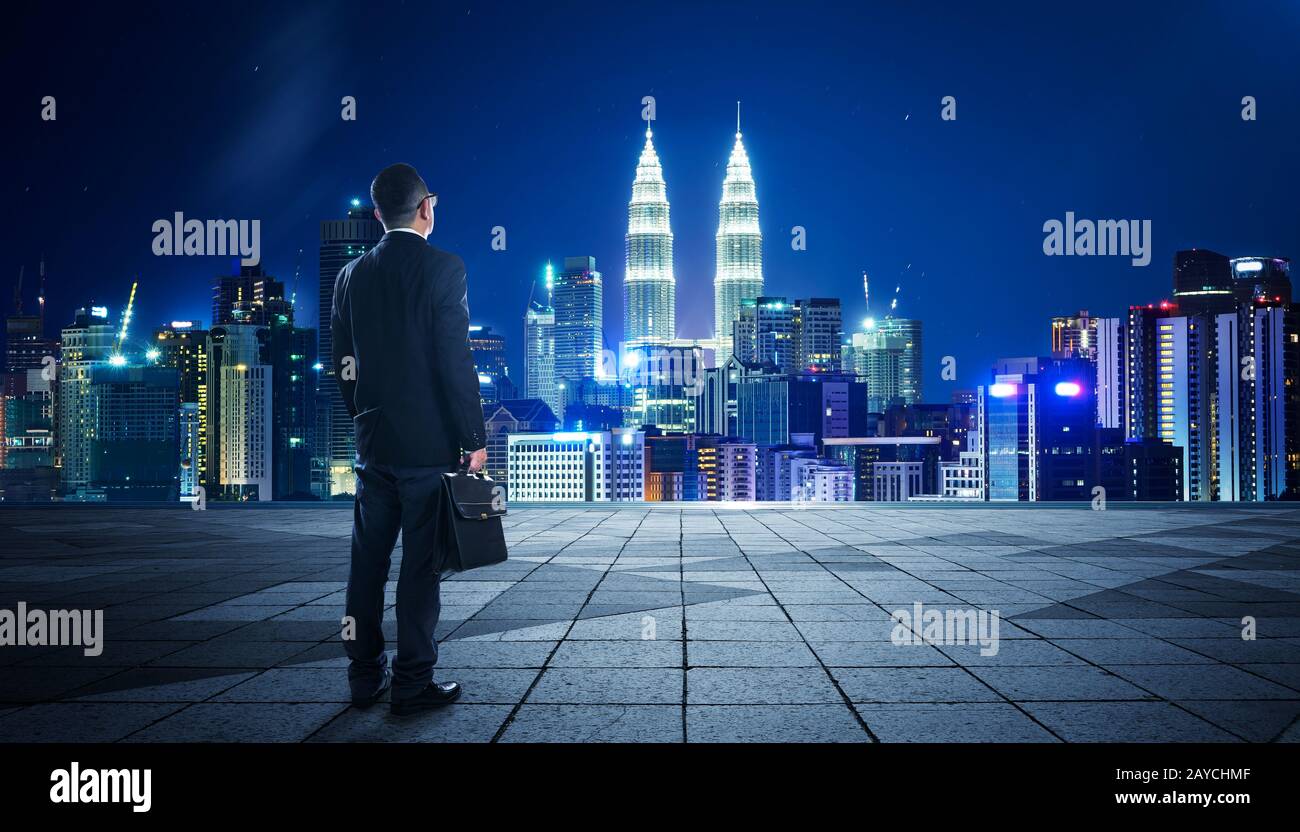 Vista posteriore di un uomo d'affari che guarda al grande centro della città. Concetto di successo e apprezzamento. Foto Stock