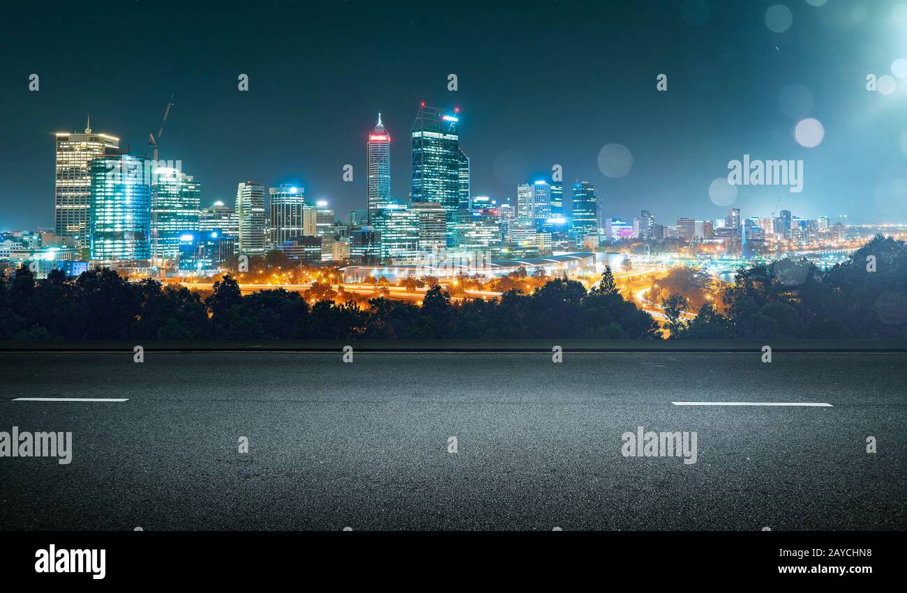 Svuotare strada asfaltata e cityscape skyline notturno con luce flare effetto bokeh di fondo . Foto Stock