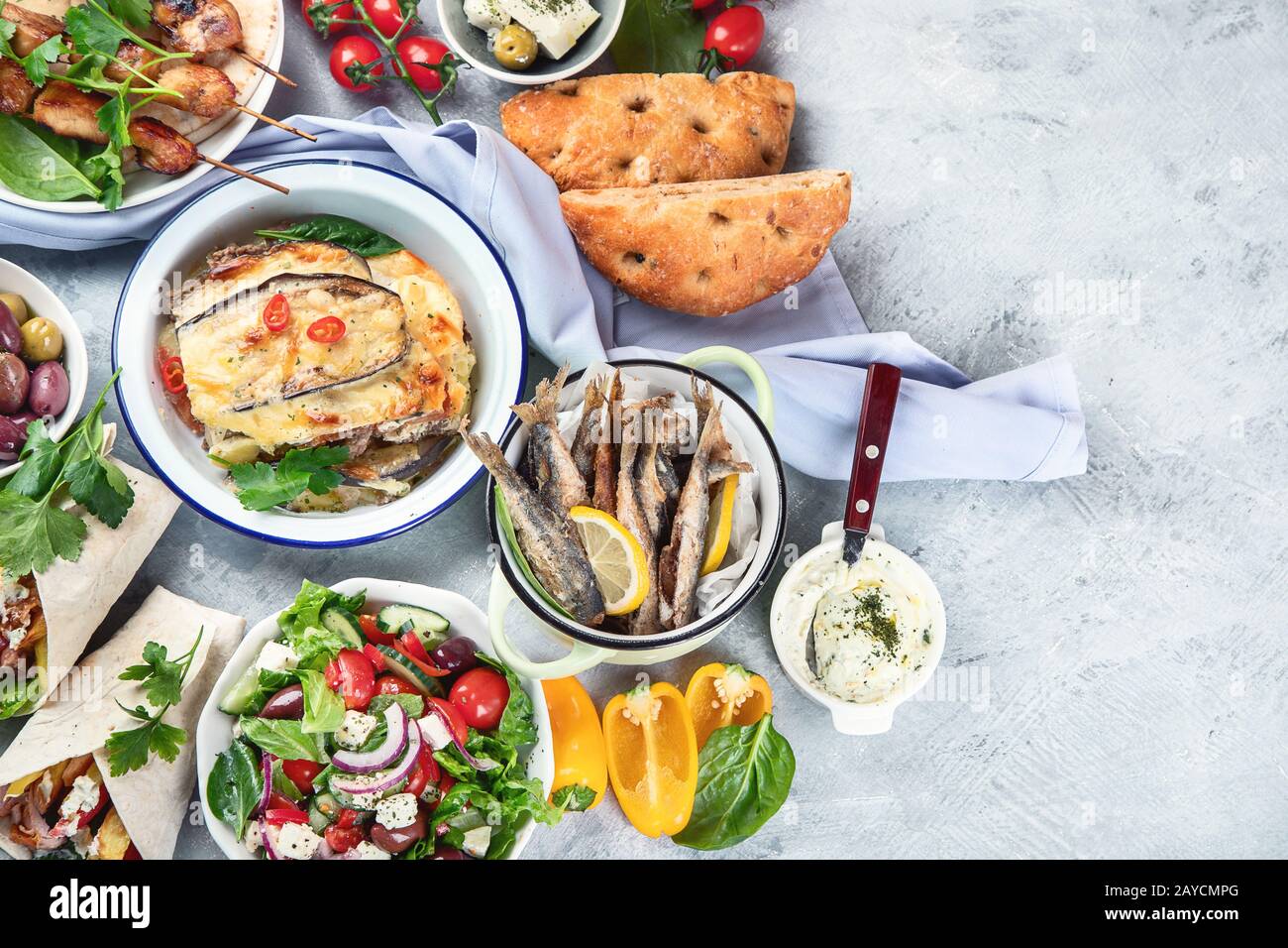 Cibo greco su sfondo grigio. Moussaka, gyros, souvlaki, pita, insalata, olive e verdure. Piatti tradizionali di diversi tipi di piatti greci. Vista dall'alto con Foto Stock