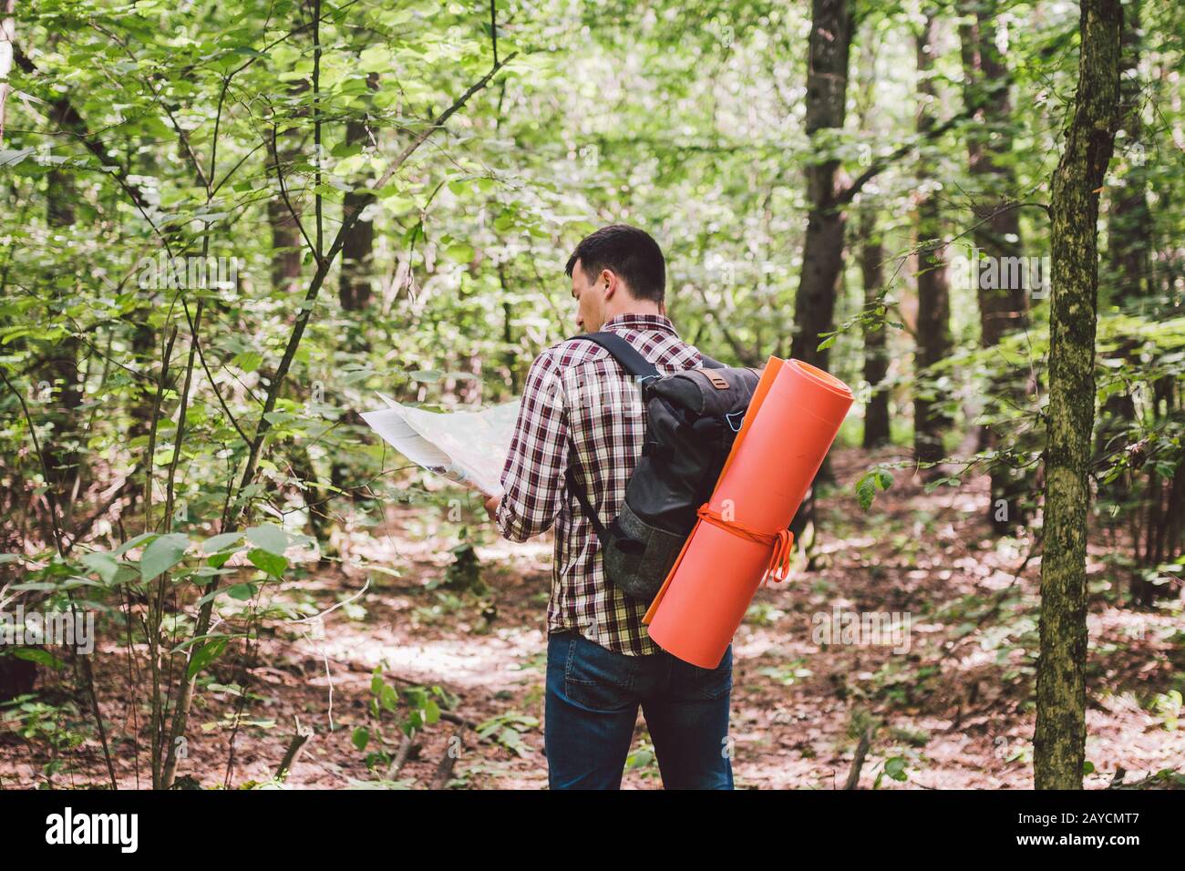 Uomo con zaino e mappa di ricerca indicazioni in zona selvaggia. Tourist con zaino utilizzando la mappa in foresta. Concetto di turismo ho Foto Stock