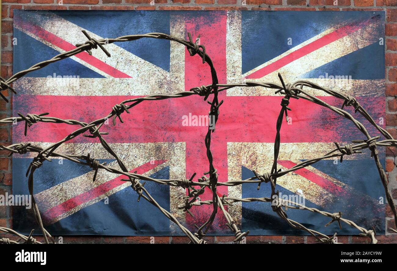 filo spinato di fronte a un vecchio jack unione macchiato sporco bandiera britannica con bordi scuri sbriciolati su un muro di mattoni sfondo brexit Foto Stock