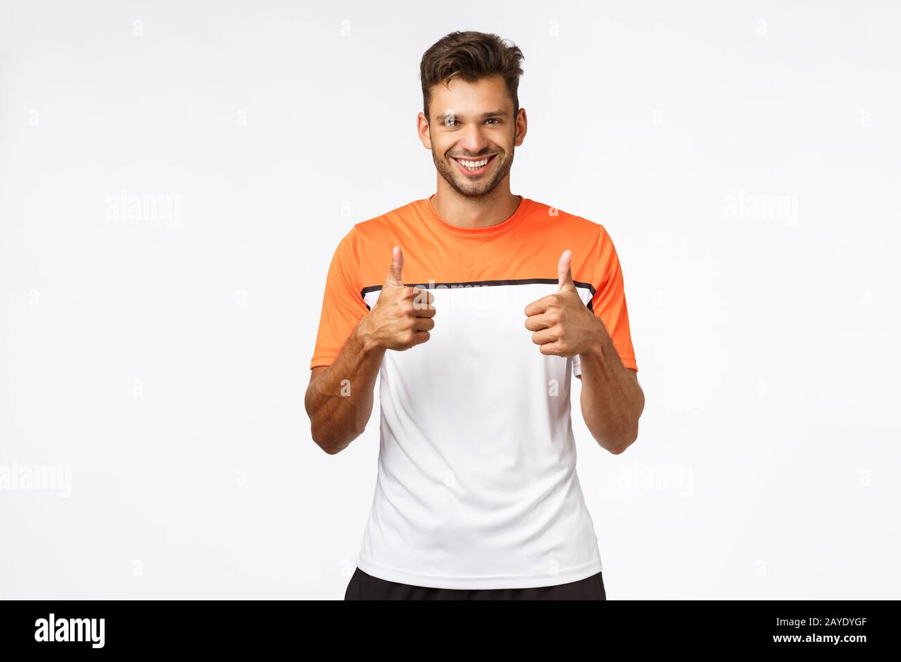 Bel giovane uomo caucasico in sport t-shirt, encrourage amico continuare a andare, il vostro fare bene, mostrando pollici-up in approvazione, li Foto Stock