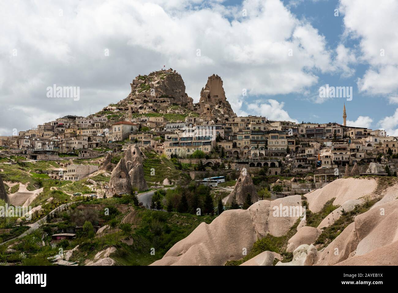 La città turistica di Uçhisar, conosciuta come il tetto della Cappadocia, e il castello; vista dall'esterno sotto un cielo blu nuvoloso luminoso Foto Stock