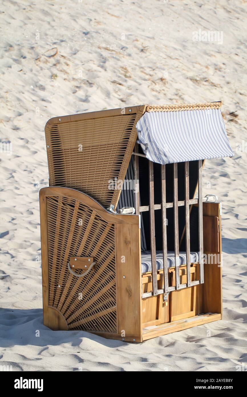 Una sedia da spiaggia chiusa si trova solo sulla spiaggia del Mar Baltico Foto Stock