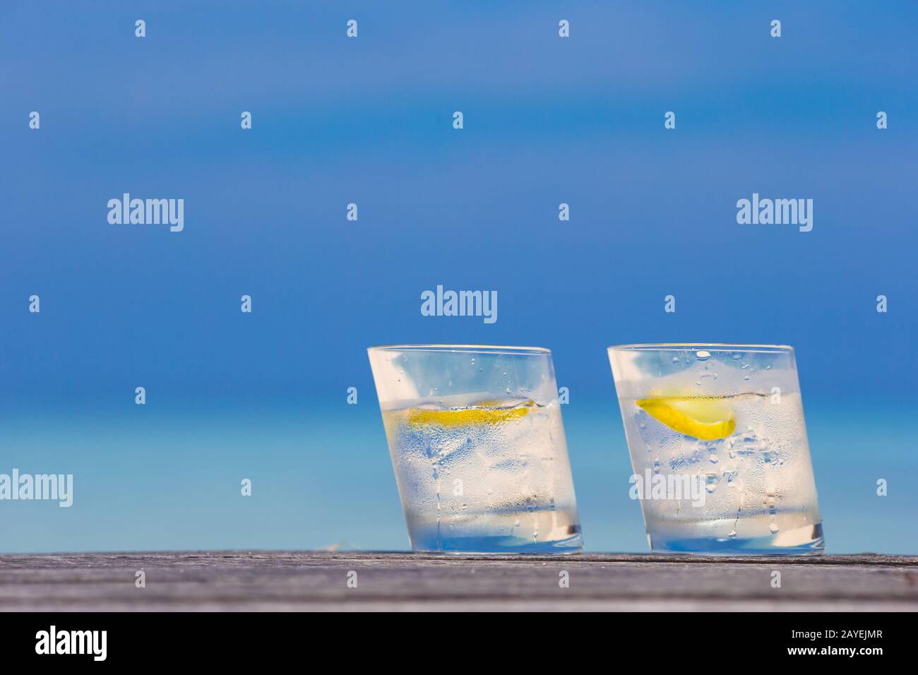 Bicchieri di acque con il limone su legno su sfondo del mare Foto Stock