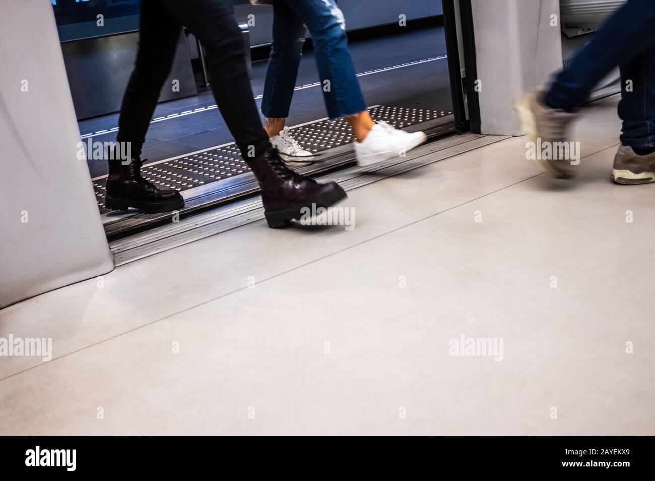 Motion passeggeri sfocati che entrano alla porta del carro in una stazione della metropolitana di Brescia (Lombardia, Italia). Pavimentazione tattile per guidare le persone cieche. Foto Stock