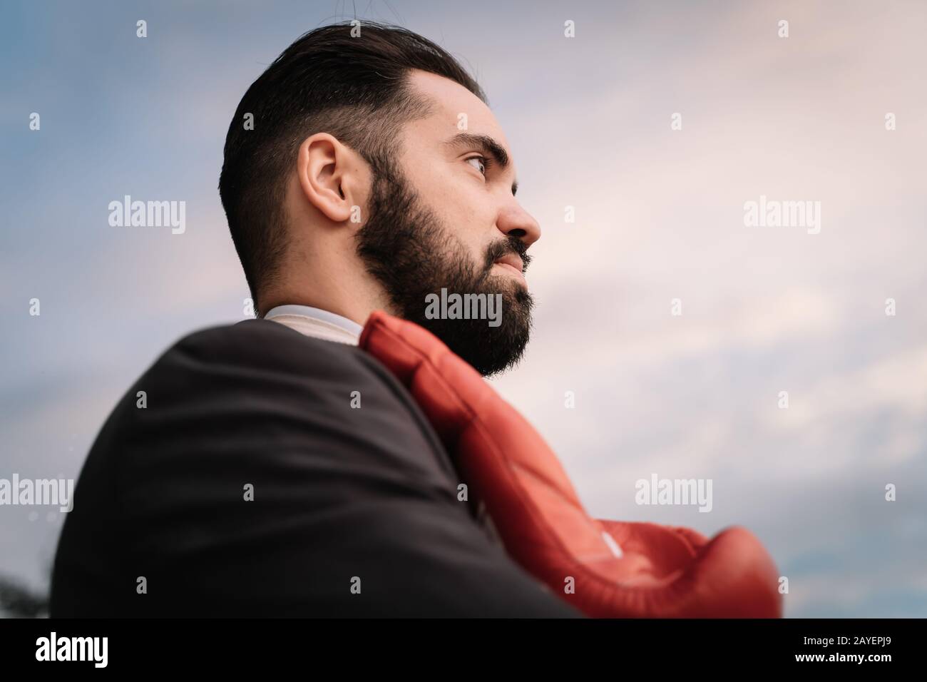 Profilo di un uomo d'affari in una tuta con guanti da boxe rossi appesi al collo Foto Stock