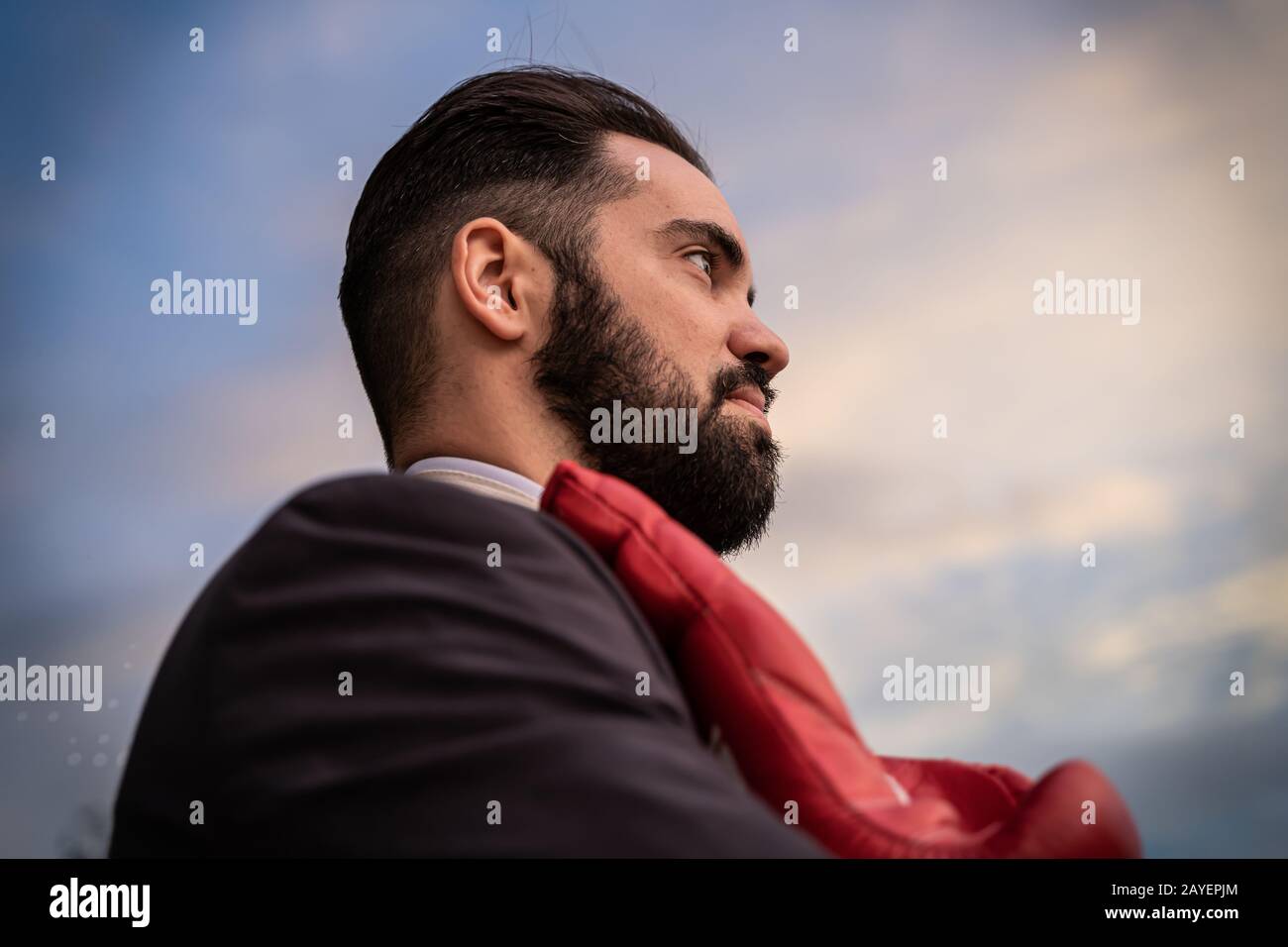 Profilo di un uomo d'affari in una tuta con guanti da boxe rossi appesi al collo Foto Stock
