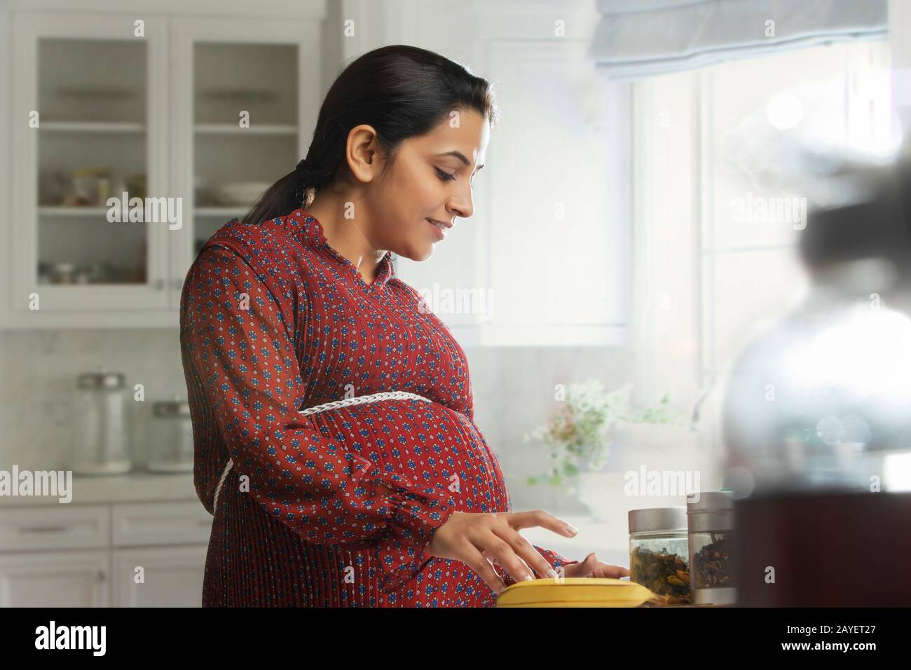 Donna incinta in piedi in cucina. Foto Stock