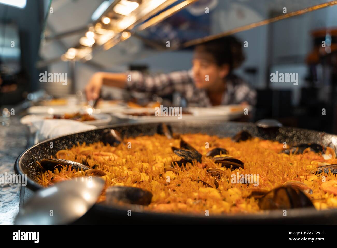 Stock foto di piatto a base di pesce a un self-service food counter con una ragazza non messa a fuoco in background afferrare cibo Foto Stock