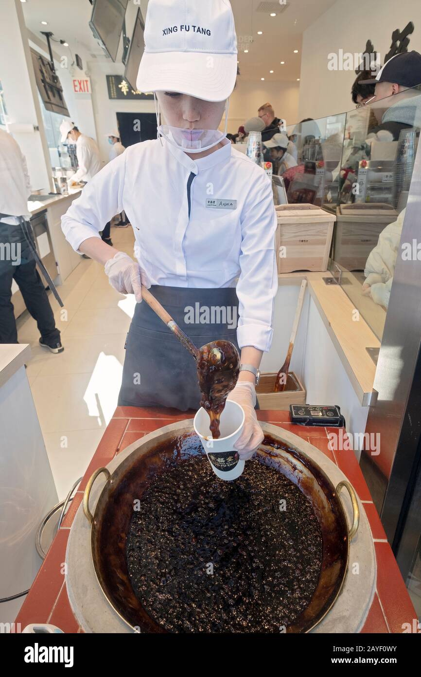 Un giovane Asiatico Americano fa una bevanda di latte di boba nella finestra a Xing fu Tang, un negozio taiwanese a Main St. A Flushing, Queens, Chinatown di New York. Foto Stock