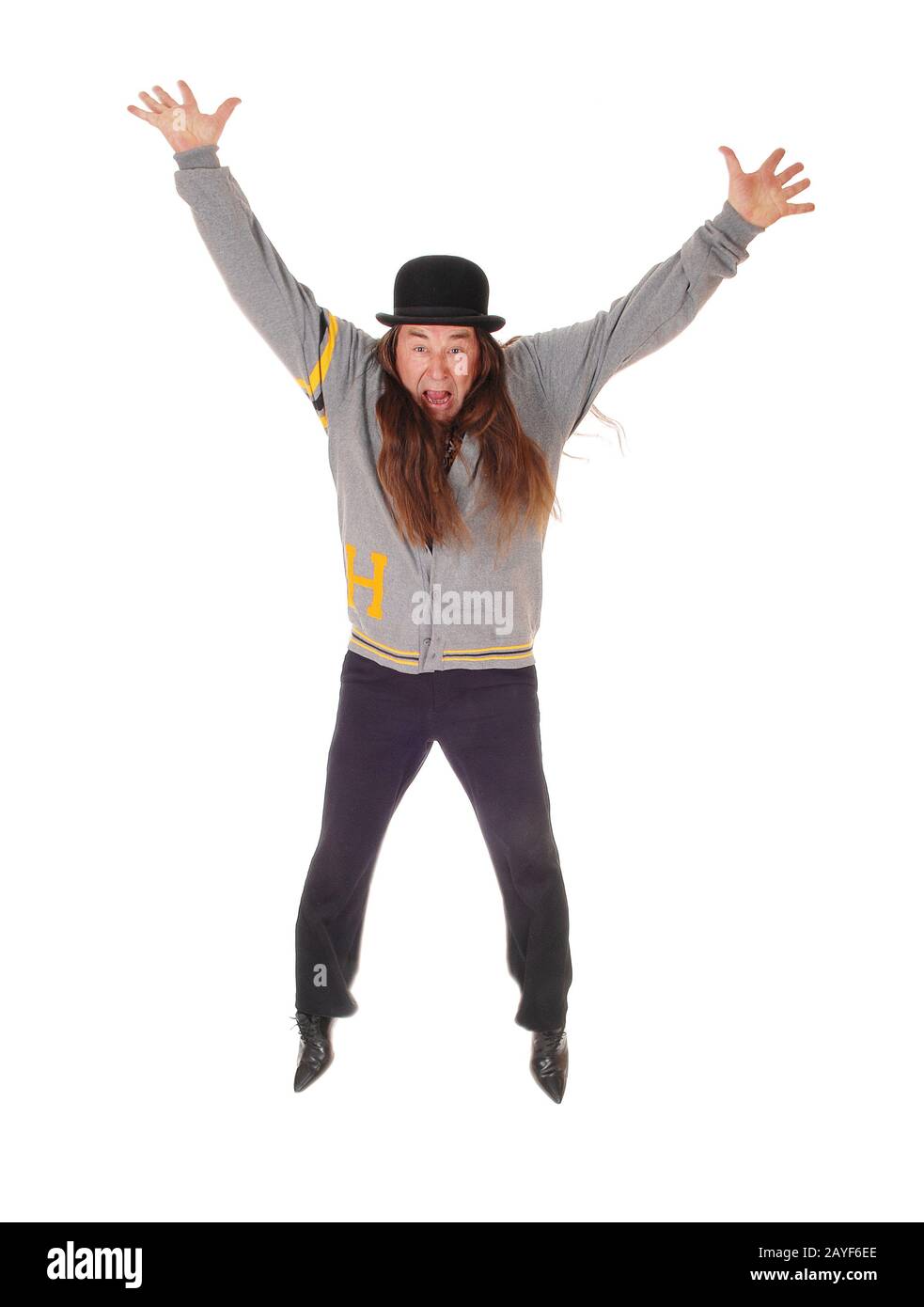 Felice salto uomo di mezza età con capelli lunghi e cappello Foto Stock