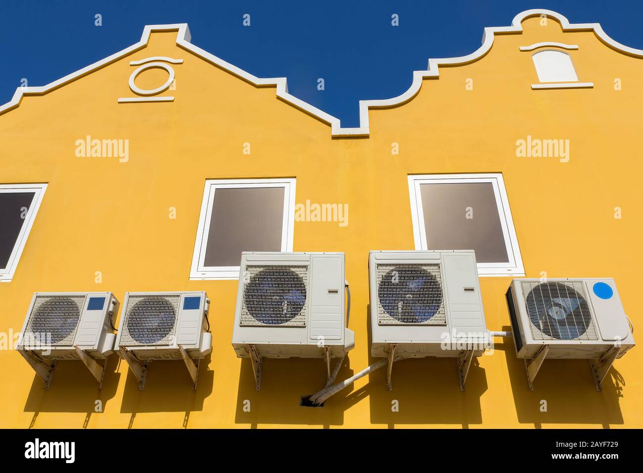 Condizionatori d'aria sulle pareti gialle delle case Foto Stock