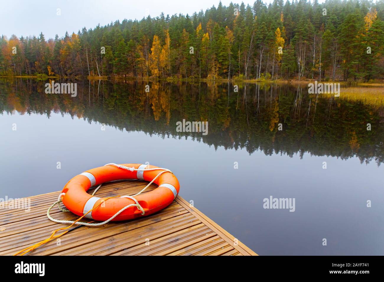 Lifebuoy arancione all'acqua del lago finlandese Foto Stock