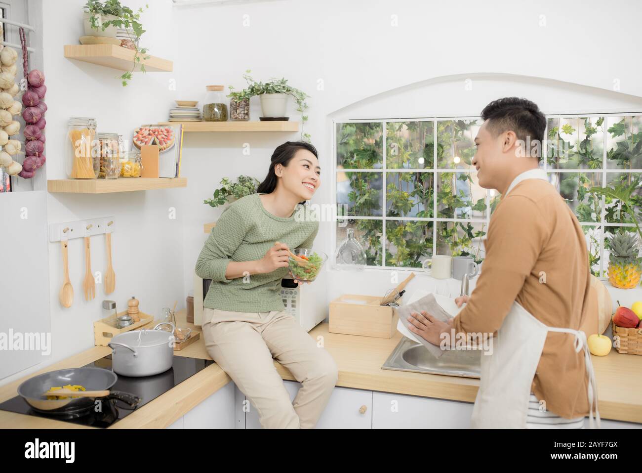 Felice coppia giovane mangiare e parlare in cucina Foto Stock