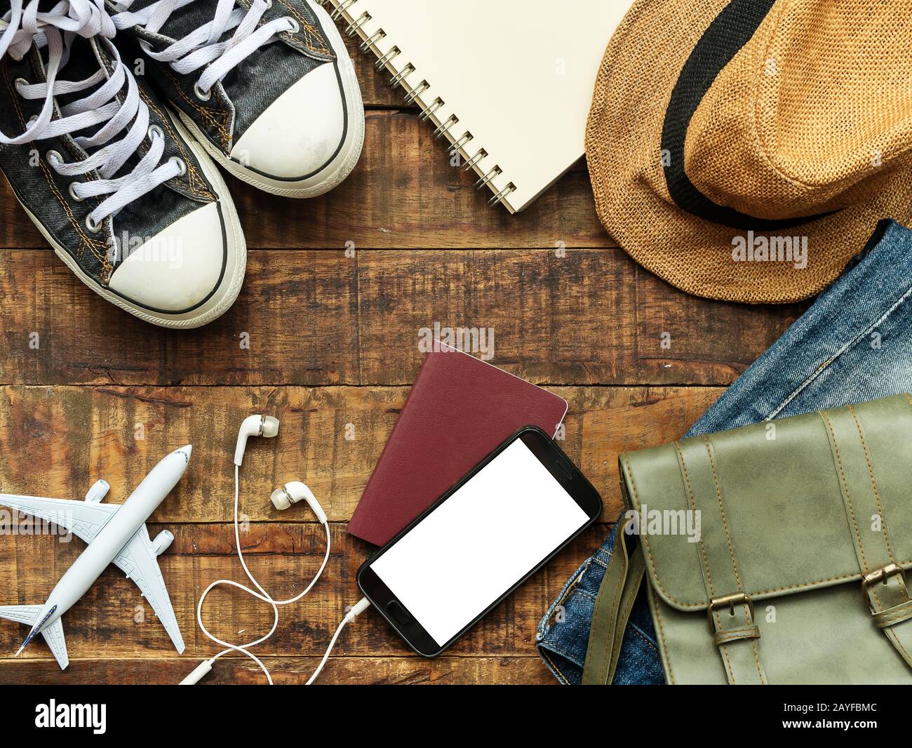 posa piatta di passaporto , cellulare , modello aereo , sneakers e accessori del viaggiatore su sfondo di legno con spazio copia. viaggio e vacanza conc Foto Stock
