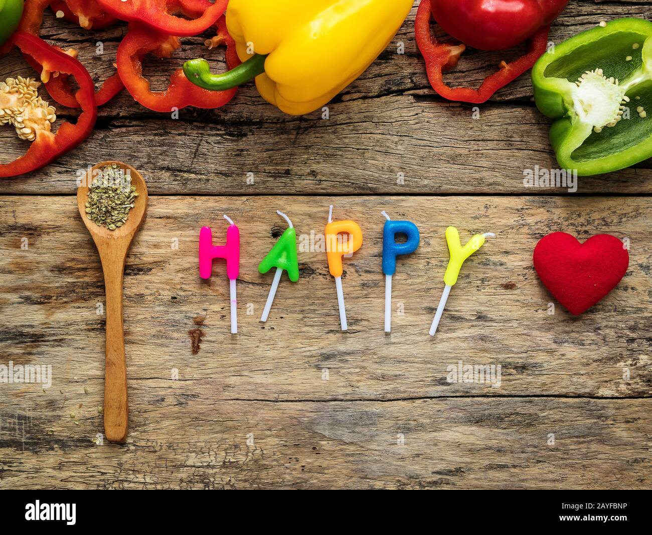 posate gli utensili da cucina con erbe, peperone colorato e la parola felice dalle candele su sfondo di legno. vista dall'alto con spazio per le copie. mangiate Foto Stock