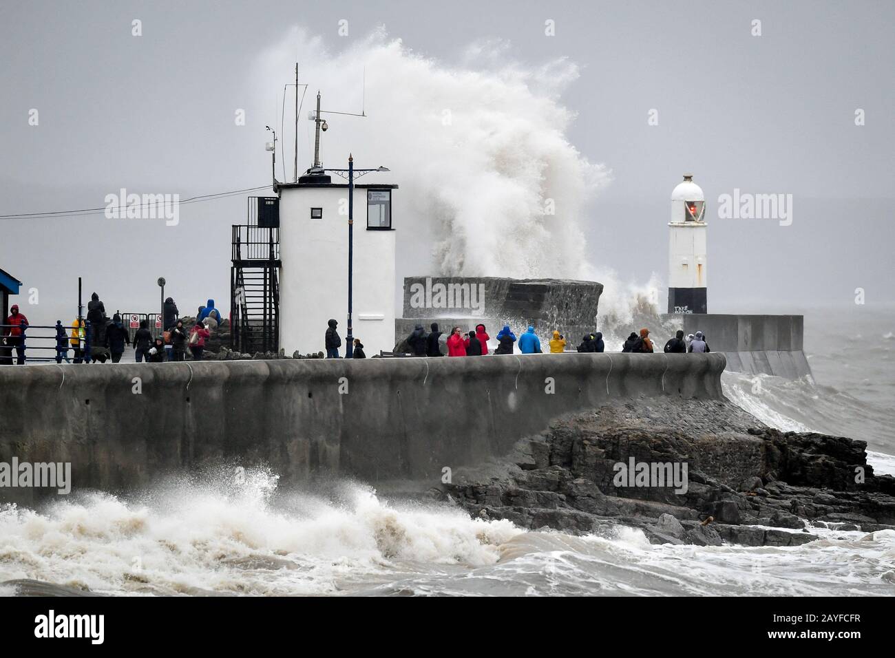 La gente guarda le onde e i mari accidentati che si infrangono contro il muro del porto a Porthcawl, Galles, mentre il Regno Unito è minacciato da un'interruzione del tempo per il secondo fine settimana di fila, come fa a capolino Storm Dennis. Foto Stock