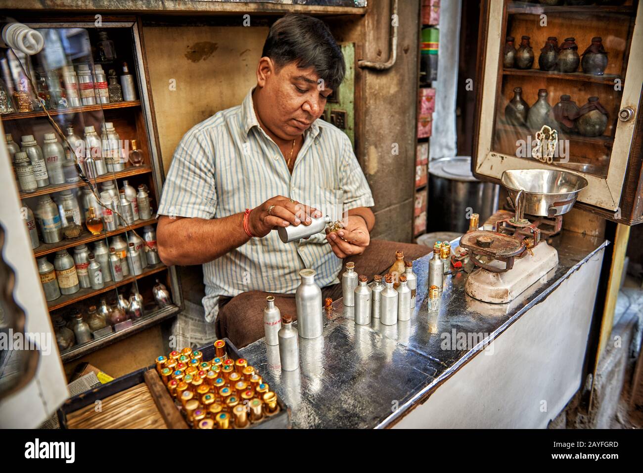 Uomo nel negozio di profumi che mescola fragranze, colorato streetlife sul mercato di Jodhpur, Rajasthan, India Foto Stock