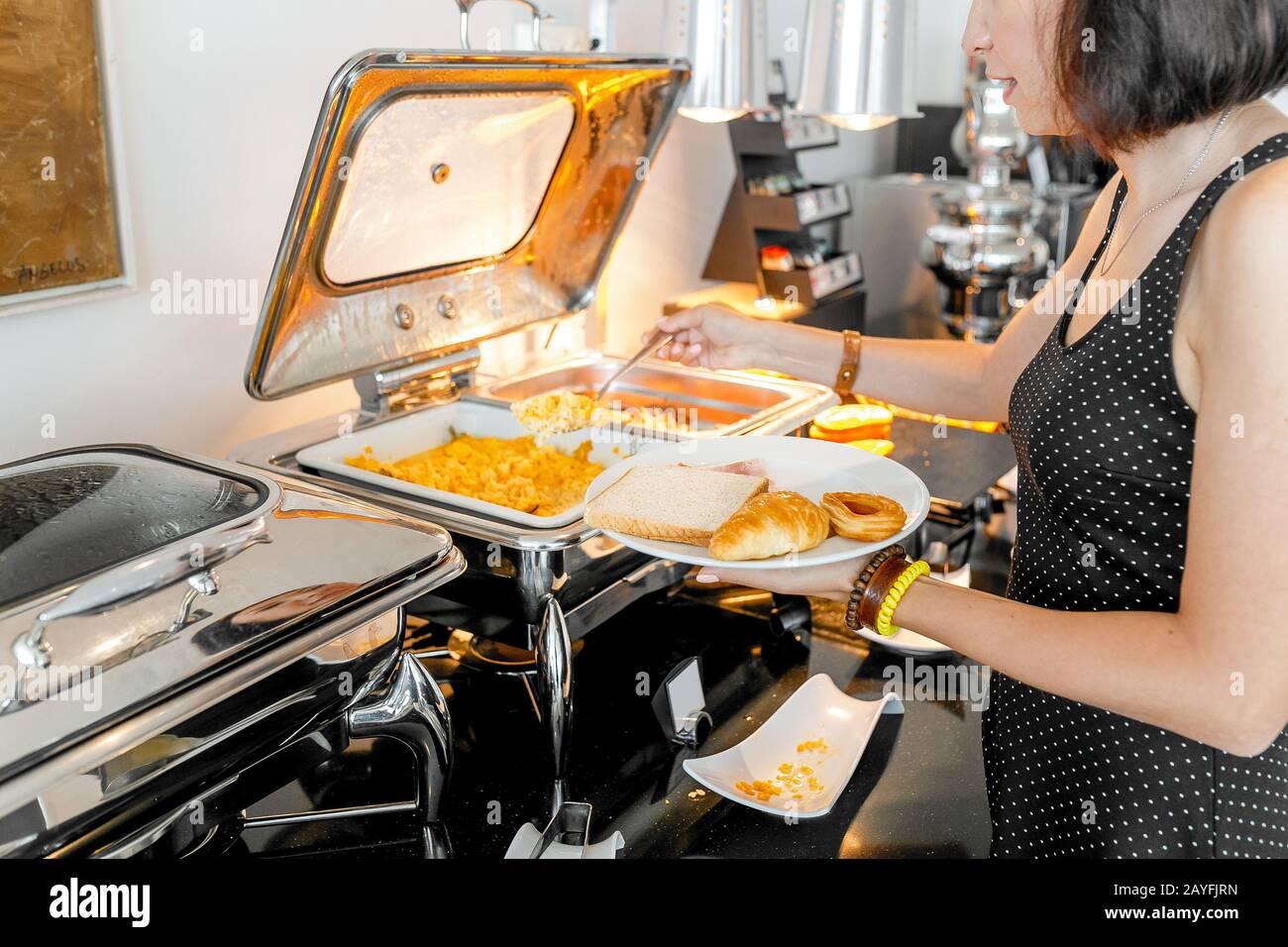 Donna che raccoglie cibo a tutti si può mangiare a buffet a colazione in hotel Foto Stock