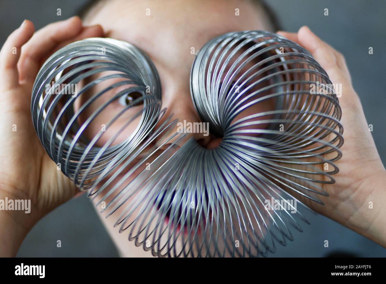 Un ragazzo guarda attraverso un giocattolo slinky. Foto Stock