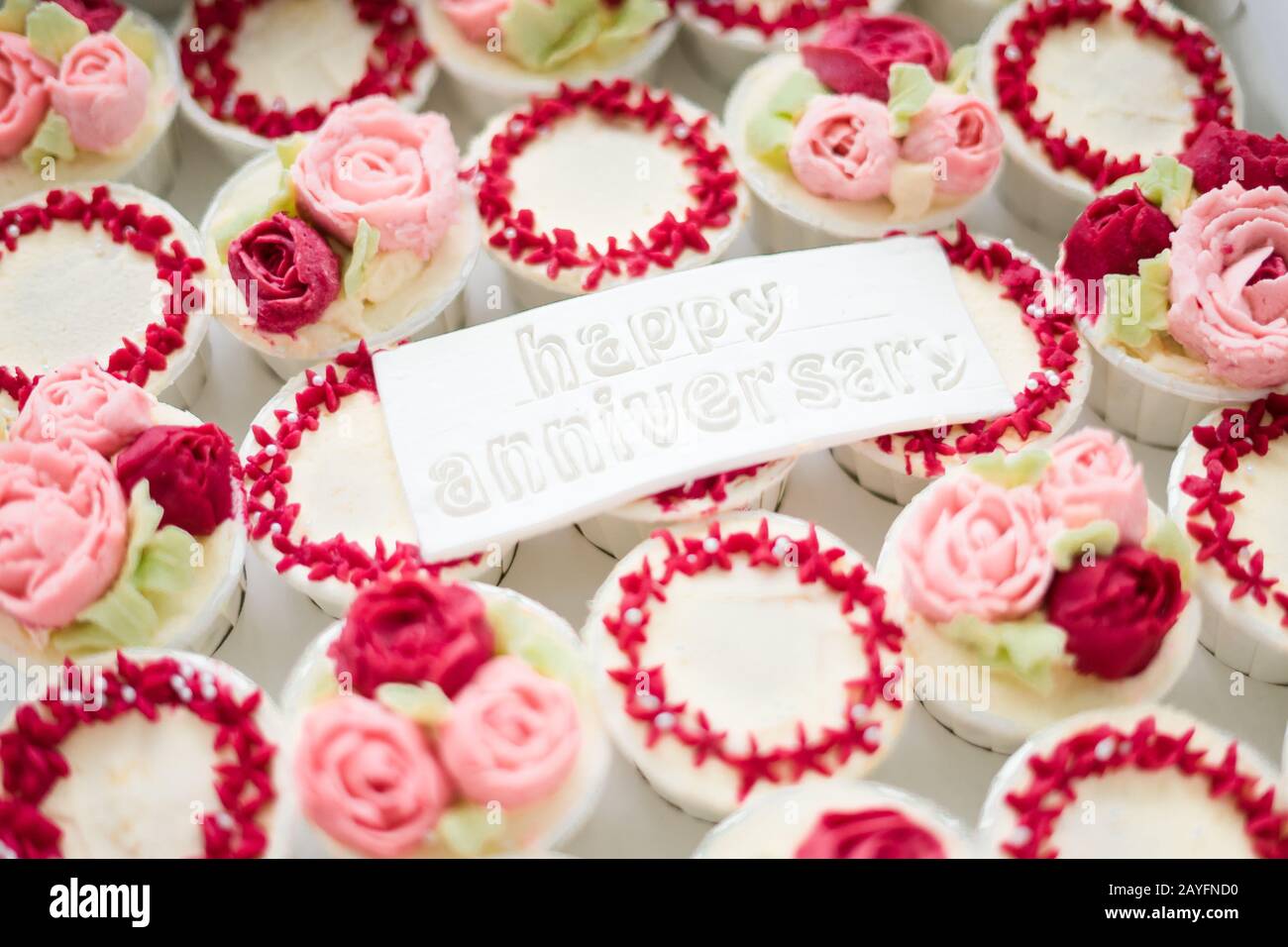 Torta di tazza Fiori di colore rosso e rosa con felice anniversario testo  sul fondante Foto stock - Alamy
