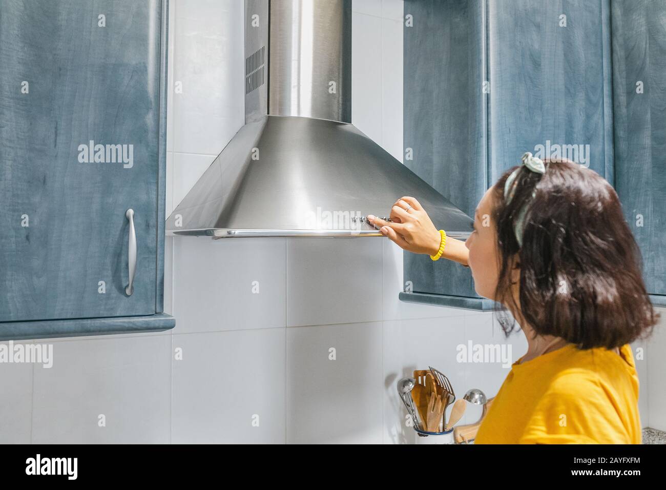 Donna attivare la ventilazione di scarico in cucina Foto Stock