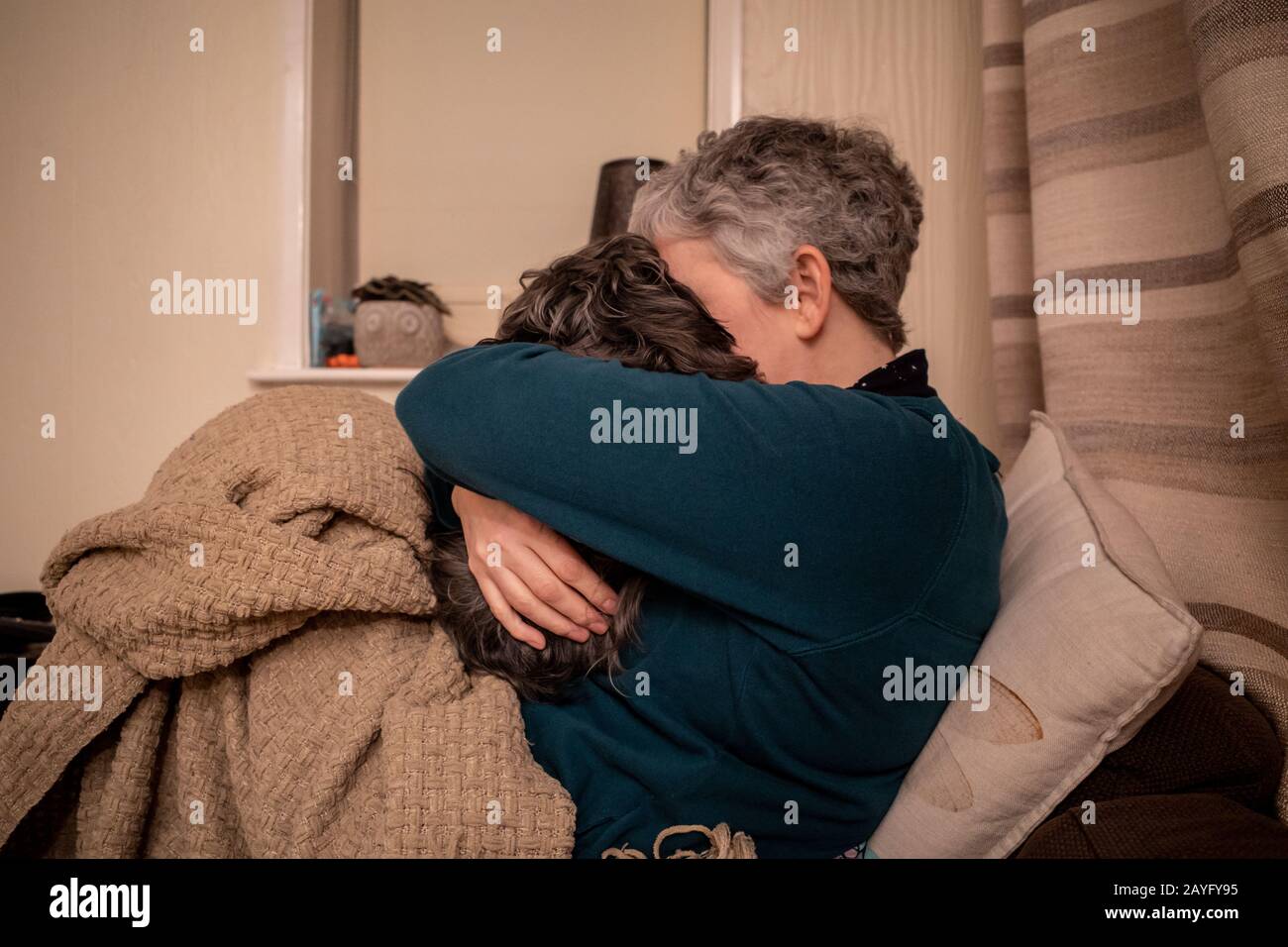 Una donna abbraccia il suo cane da compagnia a casa sul divano Foto Stock