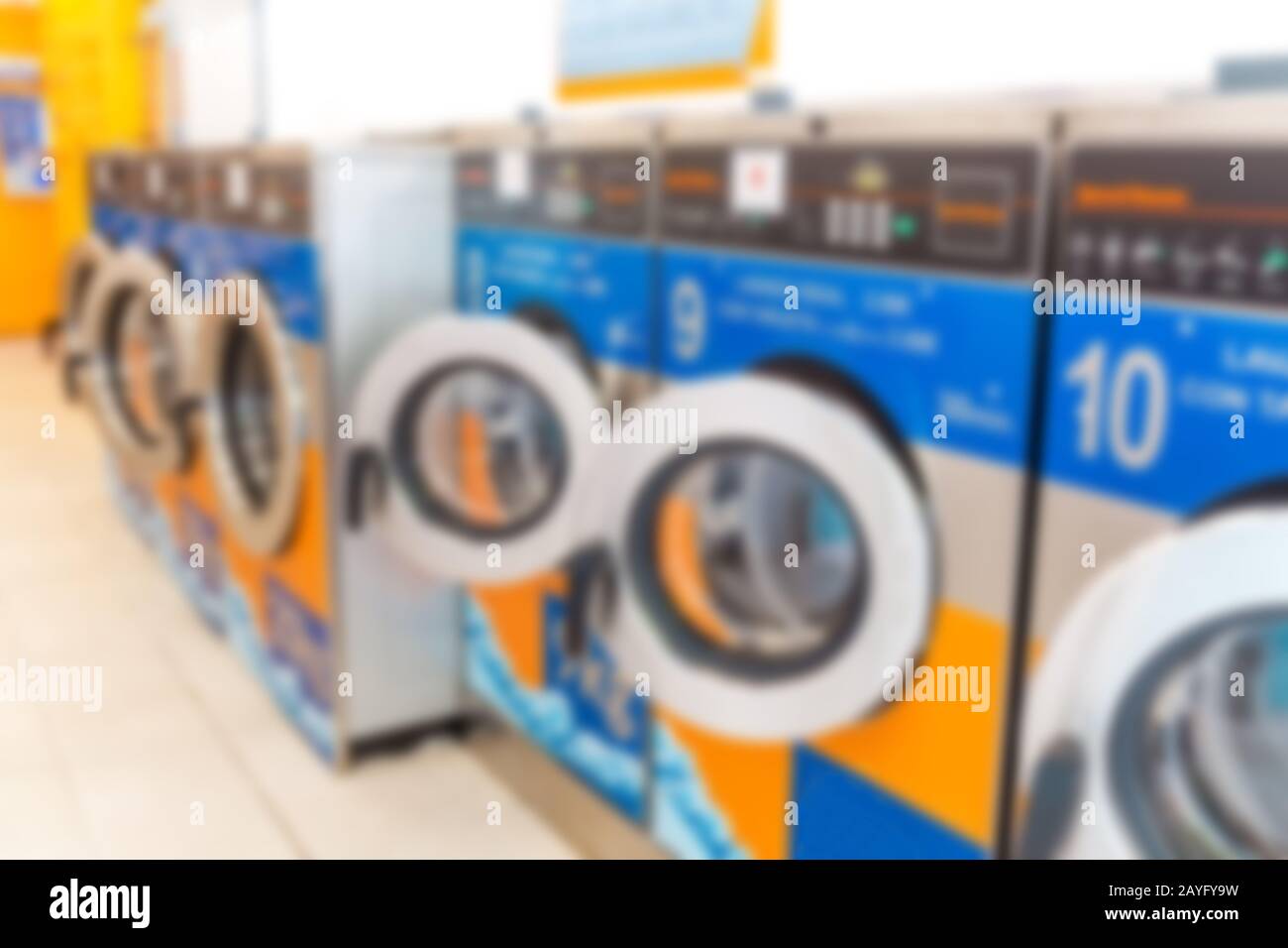 Fila di lavatrici industriali in lavanderia automatica, immagine sfocata sullo sfondo Foto Stock