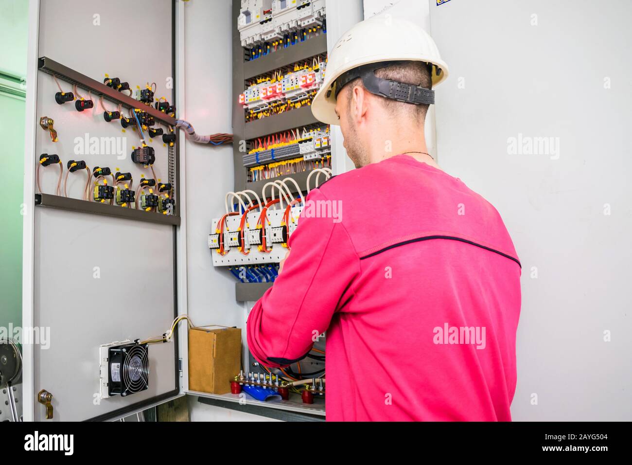 Un tecnico qualificato lavora in un quadro elettrico. L'elettricista ripara la scatola elettrica. Il lavoratore ripara le apparecchiature ad alta tensione Foto Stock