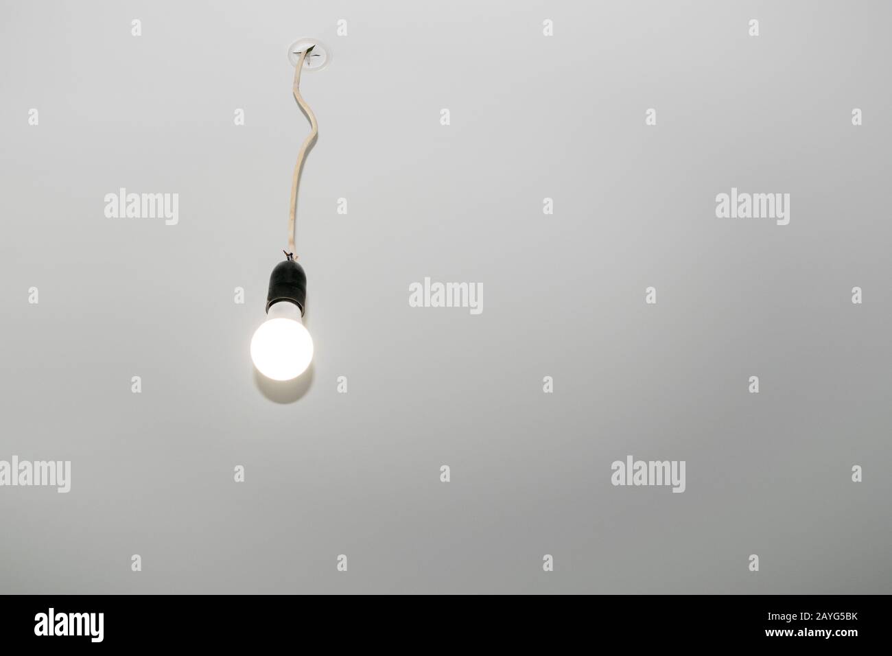 La lampadina elettrica sul filo è sospesa dal soffitto sospeso. Foto Stock