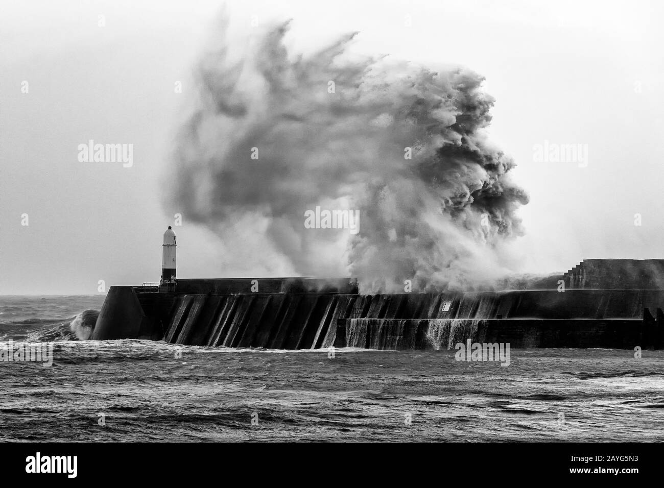 Onda bianca e nera che si infrangono sul molo di Porthcawl durante la tempesta Ciara Foto Stock