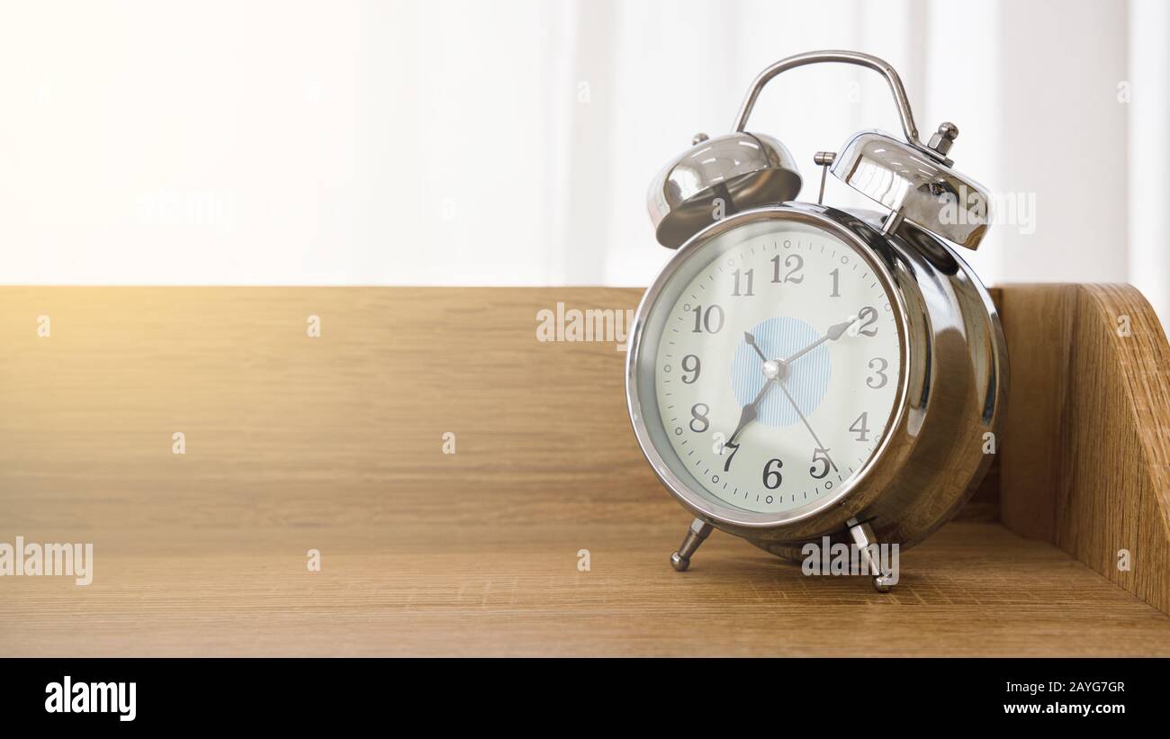 Orologio d'epoca in metallo su tavolo in legno in camera da letto con spazio copia per testo e messaggio sul lato sinistro. Foto Stock