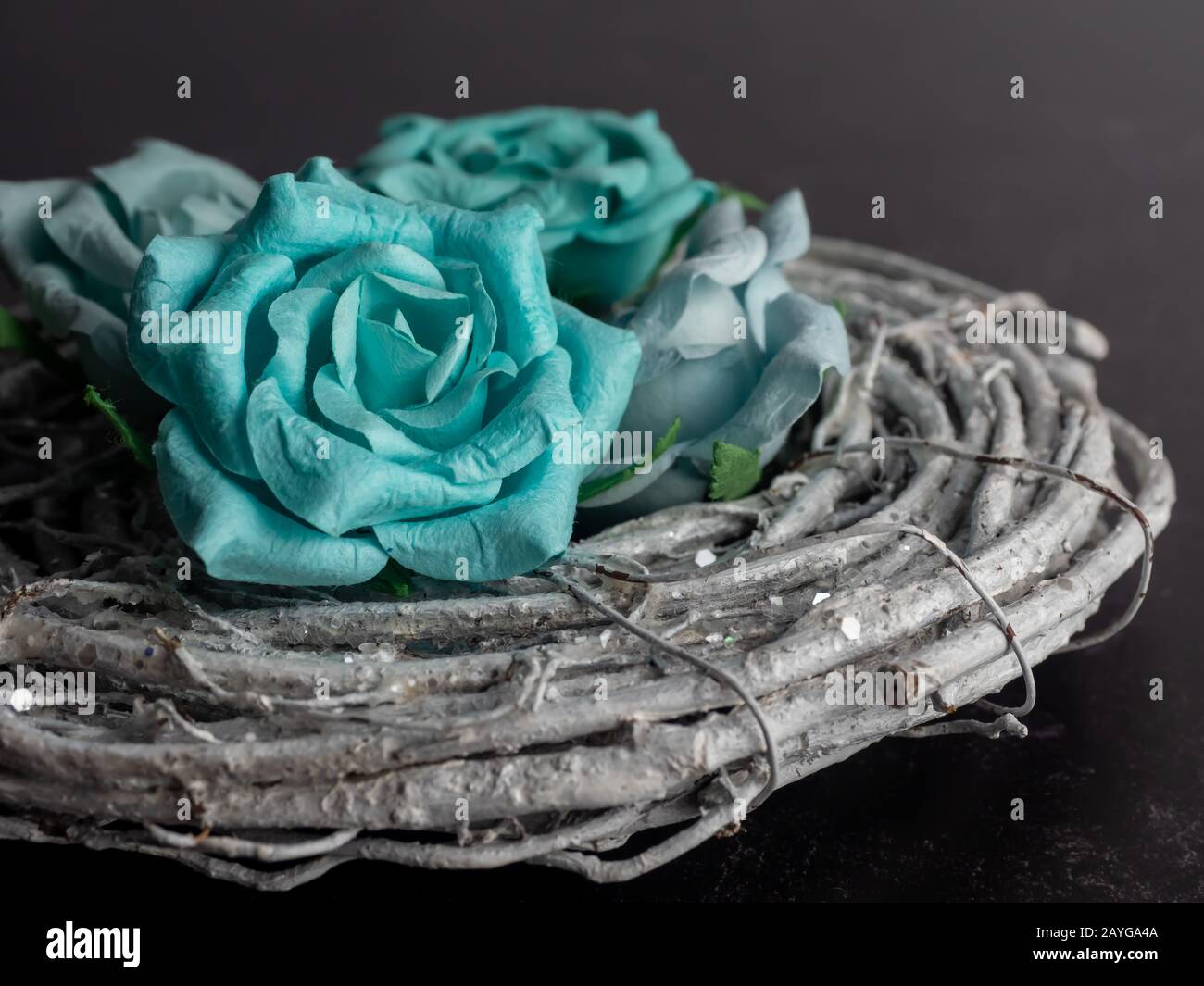 Carta blu e verde rosa fiore fioriture su legno grigio avvolto su uno sfondo nero ardesia. Grazioso arredamento di casa. Foto Stock