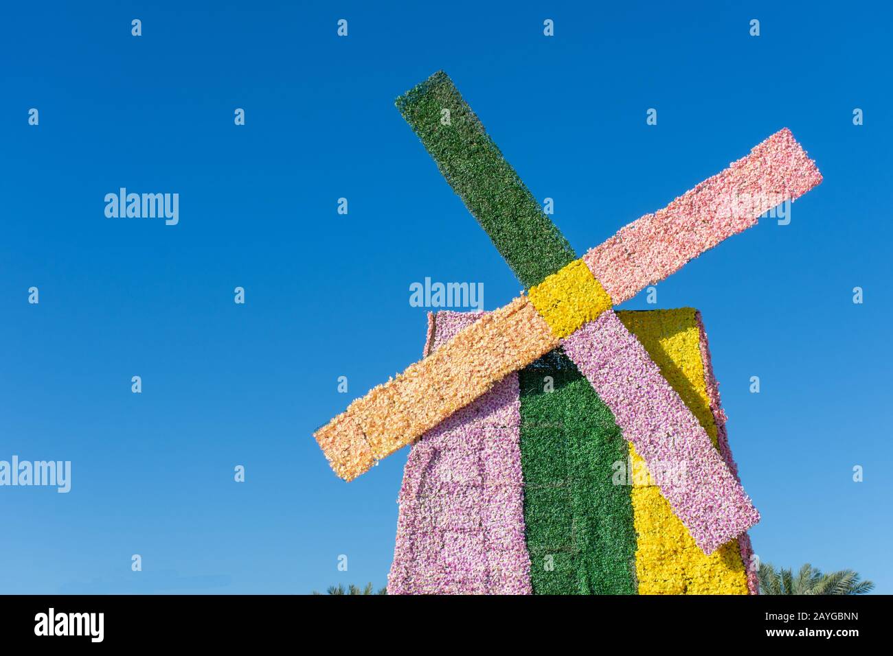 Un mulino a vento colorato in rosa, verde e giallo su un cielo blu giornata di sole in una celebrazione all'aperto. Tema o concetto olandese o olandese. Foto Stock