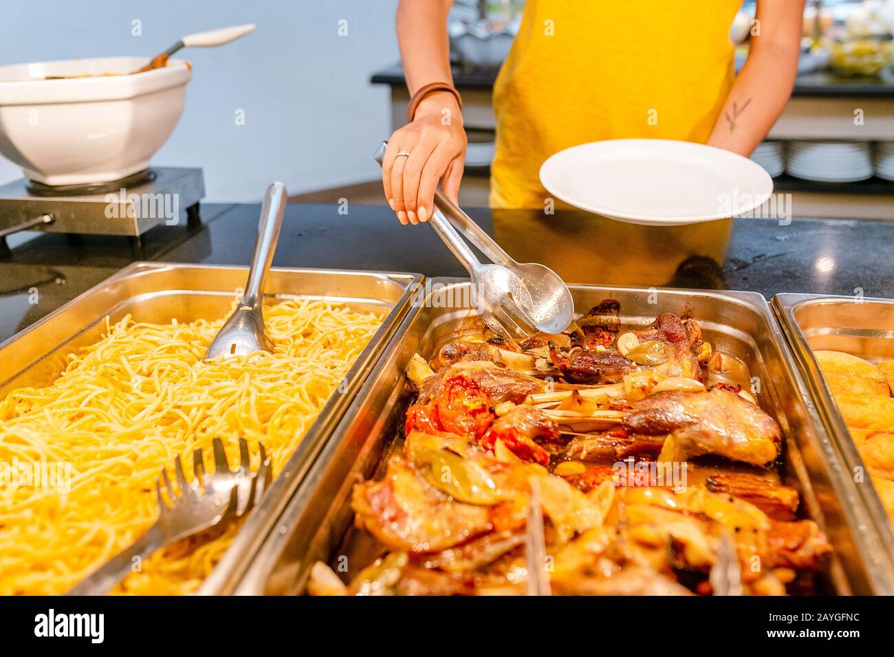 Donna che sceglie e sceglie vari spuntini e piatti su un tavolo al buffet nel ristorante dell'hotel. Tutto quello che si può mangiare Foto Stock
