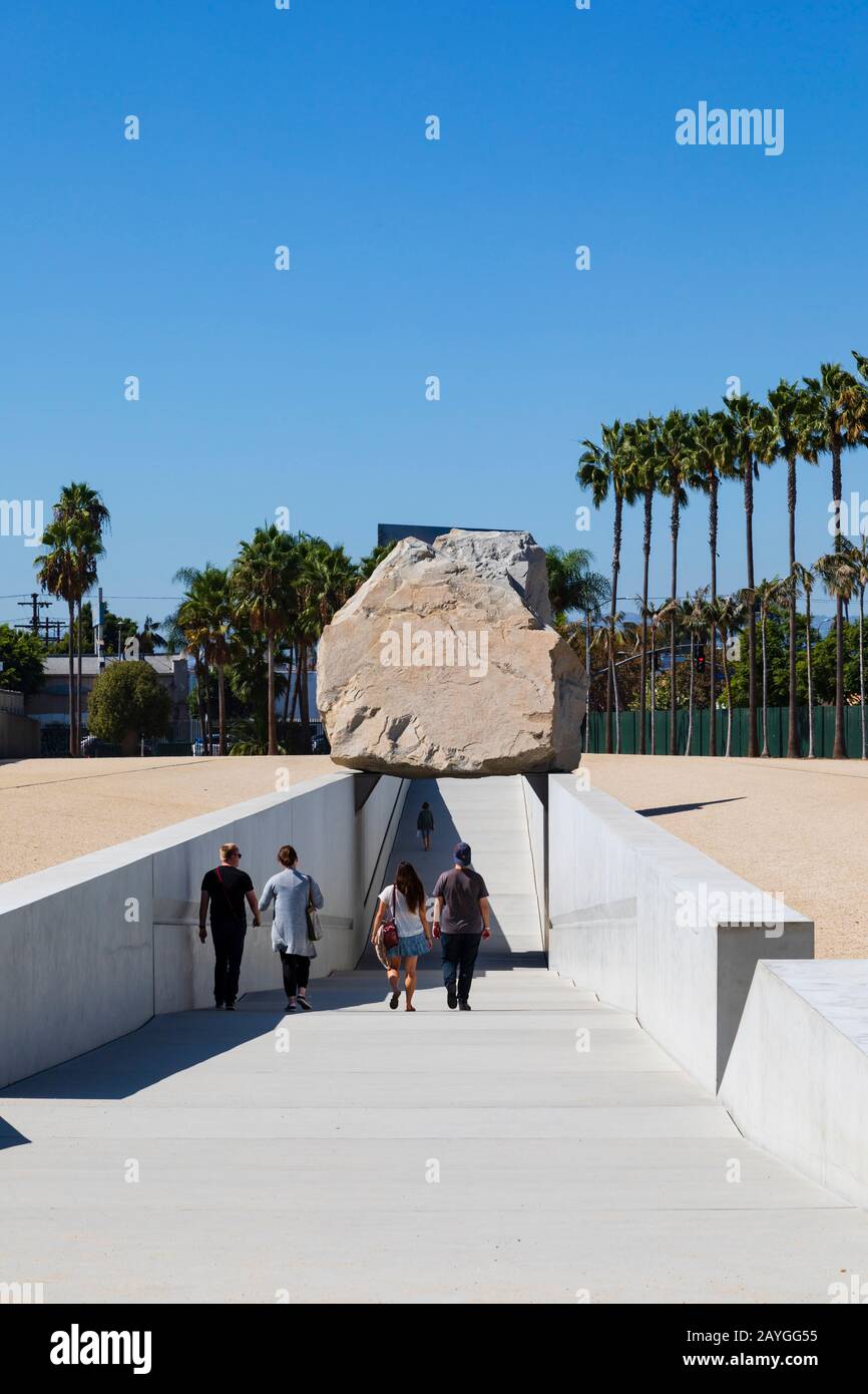 I turisti camminano sotto la "Messa levitated" scultura di arte pubblica di Michael Heizer, 2012. Resnick North Lawn a LACMA, Los Angeles, California, Stati Uniti Foto Stock
