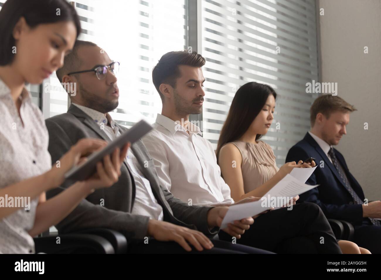 Persone diverse siedono in fila in attesa di colloquio di lavoro Foto Stock