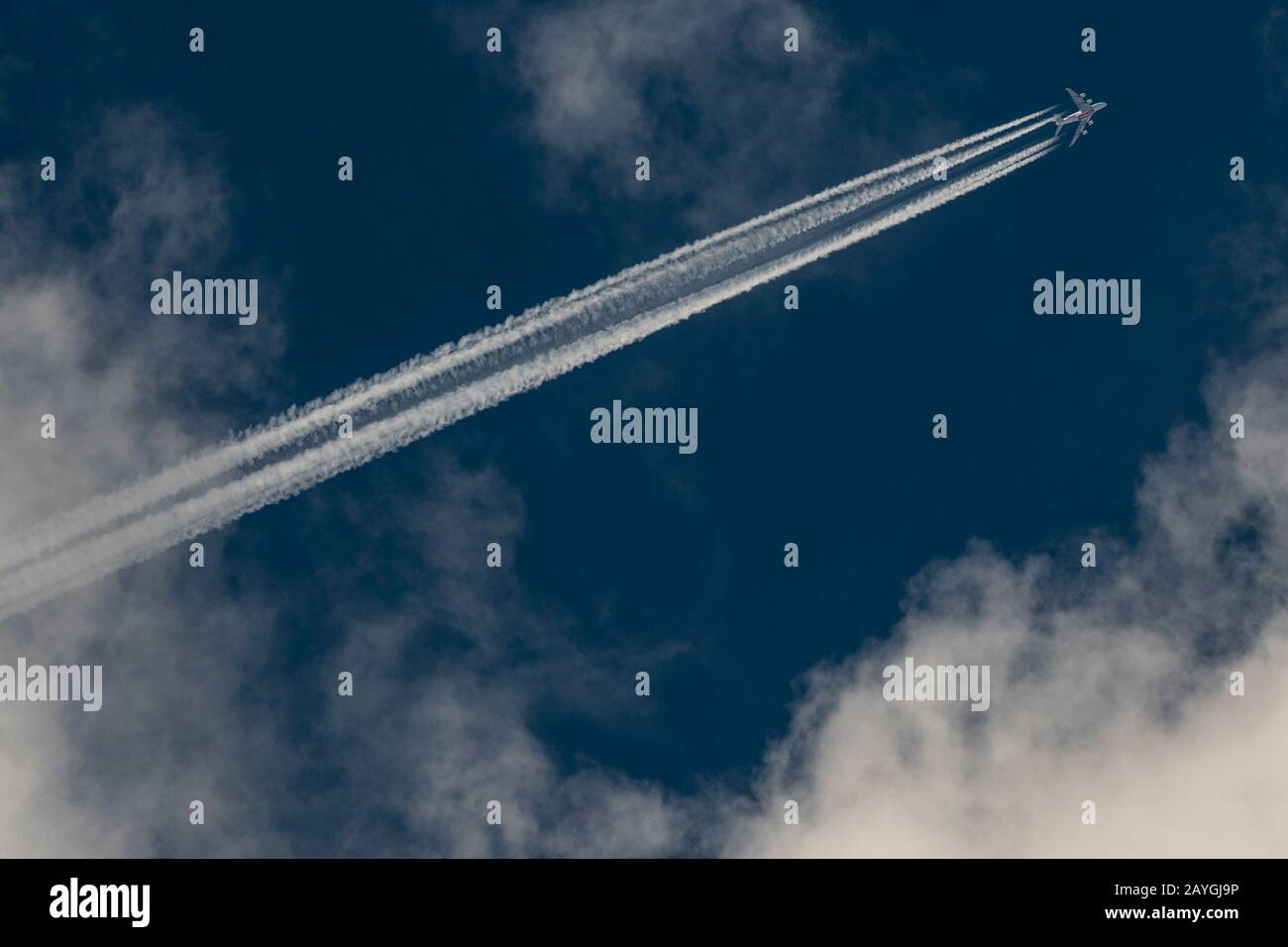 Emirates A380 lasciando contraie attraverso un cielo nuvoloso blu scuro. Foto Stock