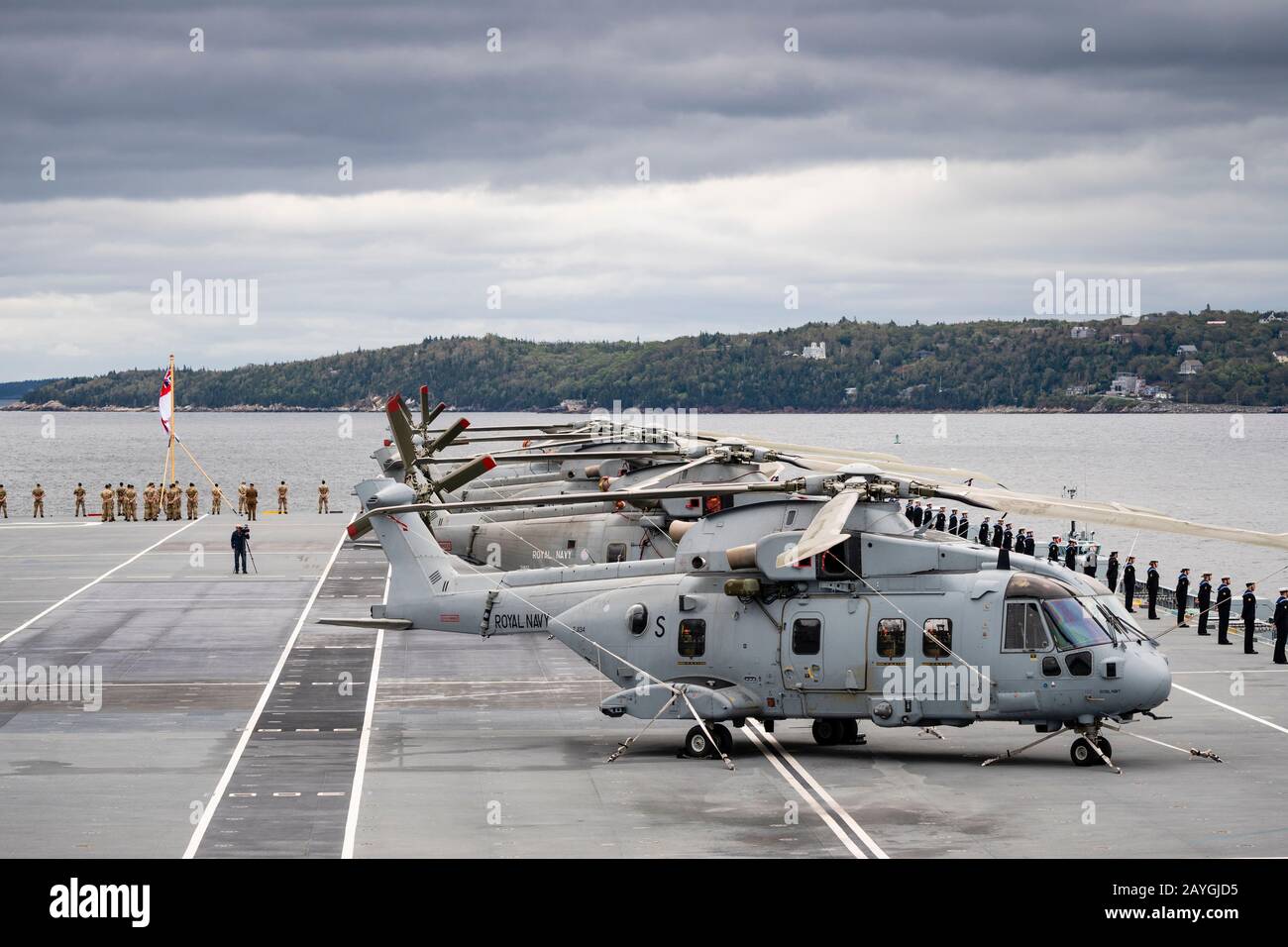 I marinai e i Royal Marines si aggirano intorno ad una linea di elicotteri Merlin a bordo del vettore della Royal Navy HMS QUEEN ELIZABETH. Foto Stock