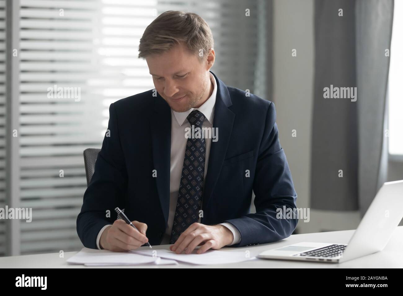 Un uomo d'affari concentrato ha messo la firma sui documenti in ufficio Foto Stock