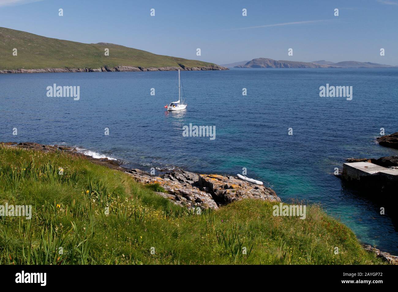 Barca a vela ancorata al luogo di atterraggio, Berneray. Guardando verso nord a Mingulay e Pabbay da Berneray, Western Isles Foto Stock