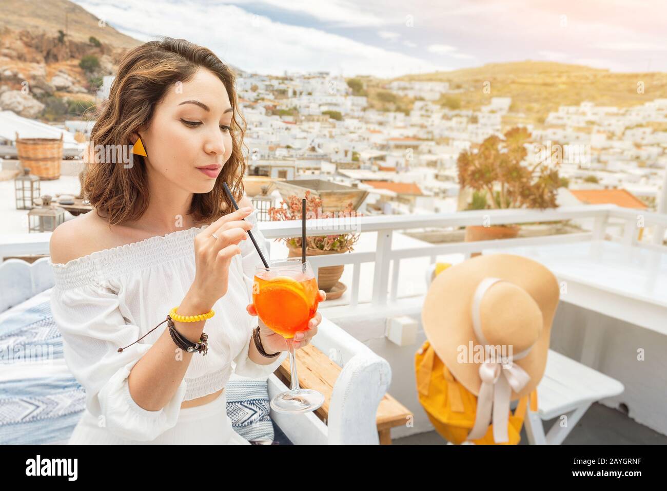 Happy asian woman godendo aperol spritz cocktail in un caffè greco. Concetto di bevande e rinfreschi Foto Stock
