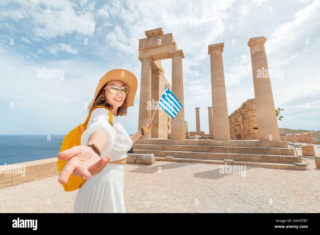 Seguimi. Donna Traveler con zaino Godendo di una splendida vista  sull'antica Acropoli greca con bandiera in mano Foto stock - Alamy